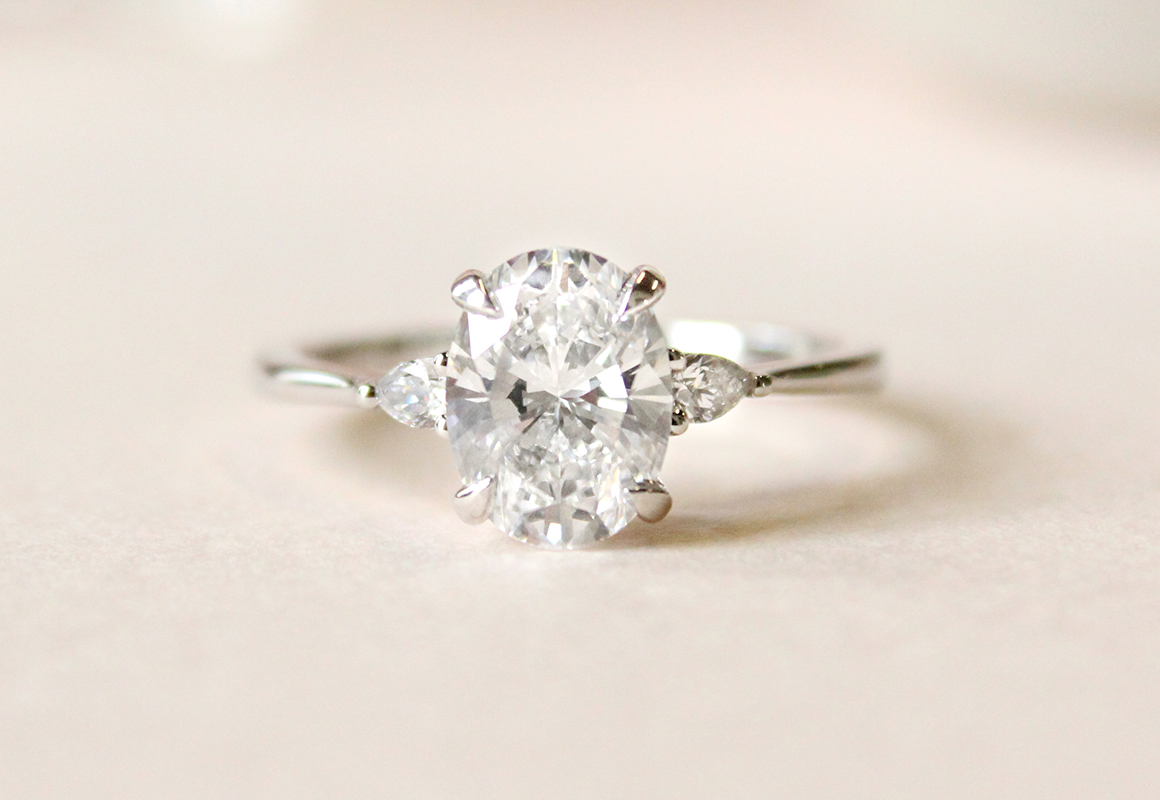 Three stone engagement ring with large, oval, moissanite center stone