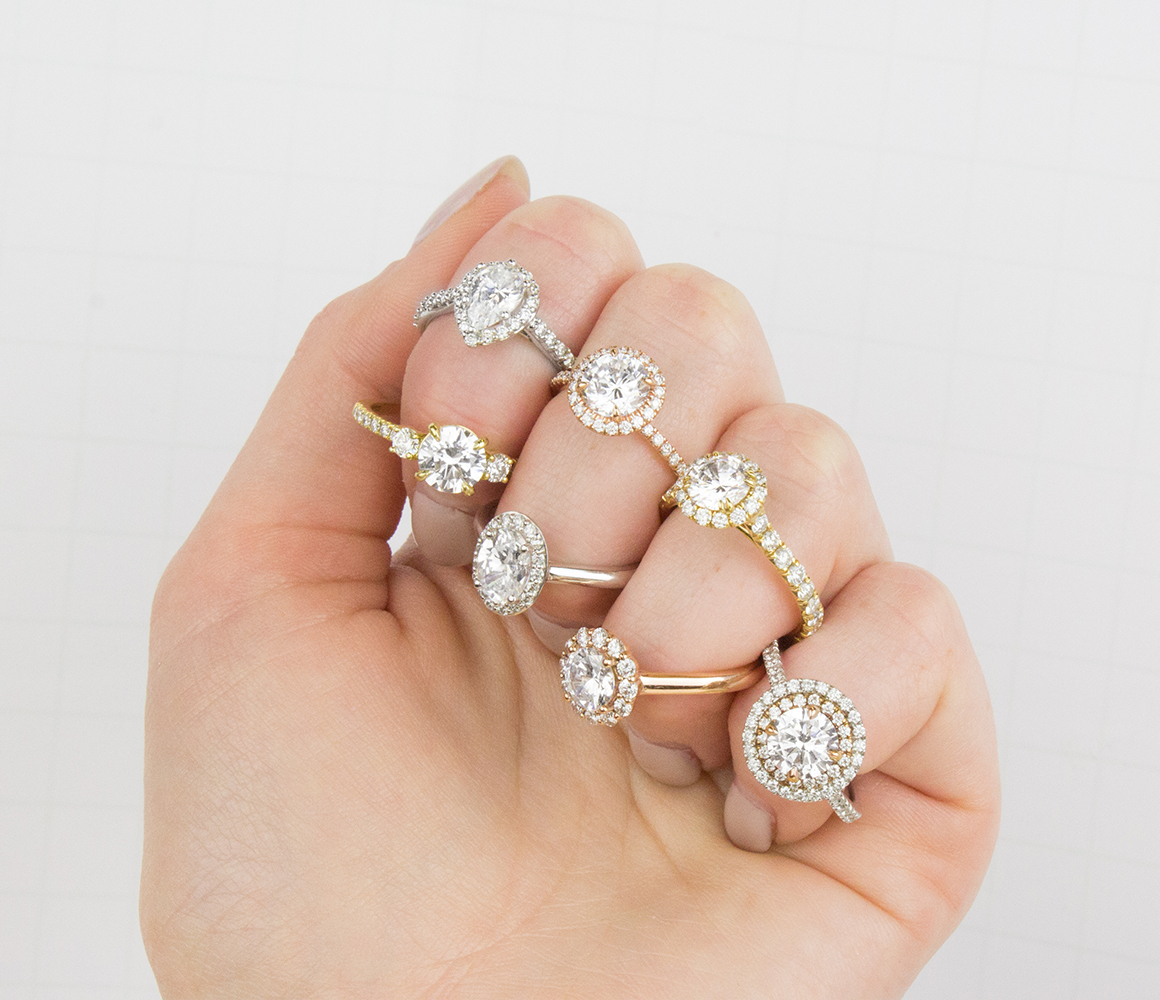 Woman’s hand with multiple white gold, rose gold, and yellow gold moissanite engagement rings on her fingers